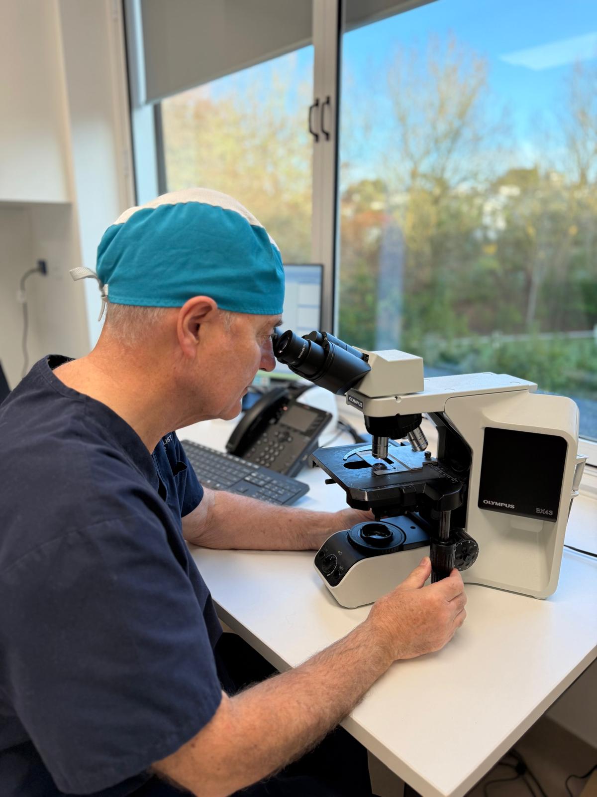 Mohs surgeon examining frozen sections under the microscope at Scars & Lasers